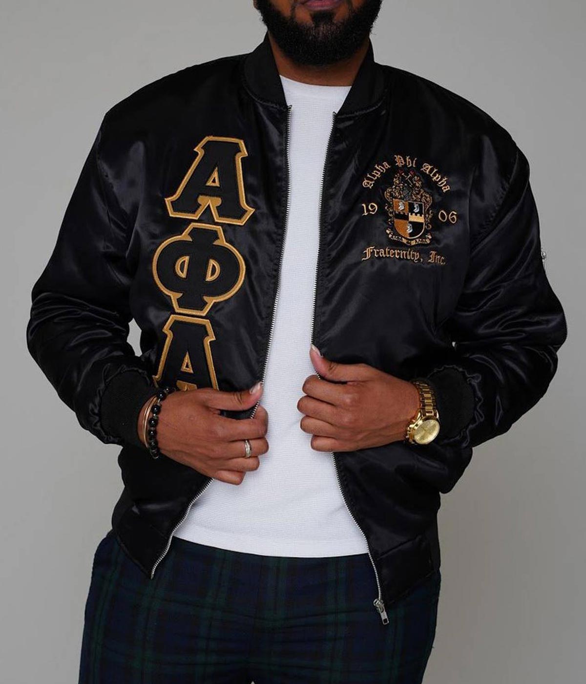 Front of black Alpha Phi Alpha bomber jacket with gold embroidery